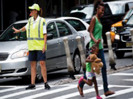 Pedestrian/Traffic manager helping a mother and daughter across a street in new york