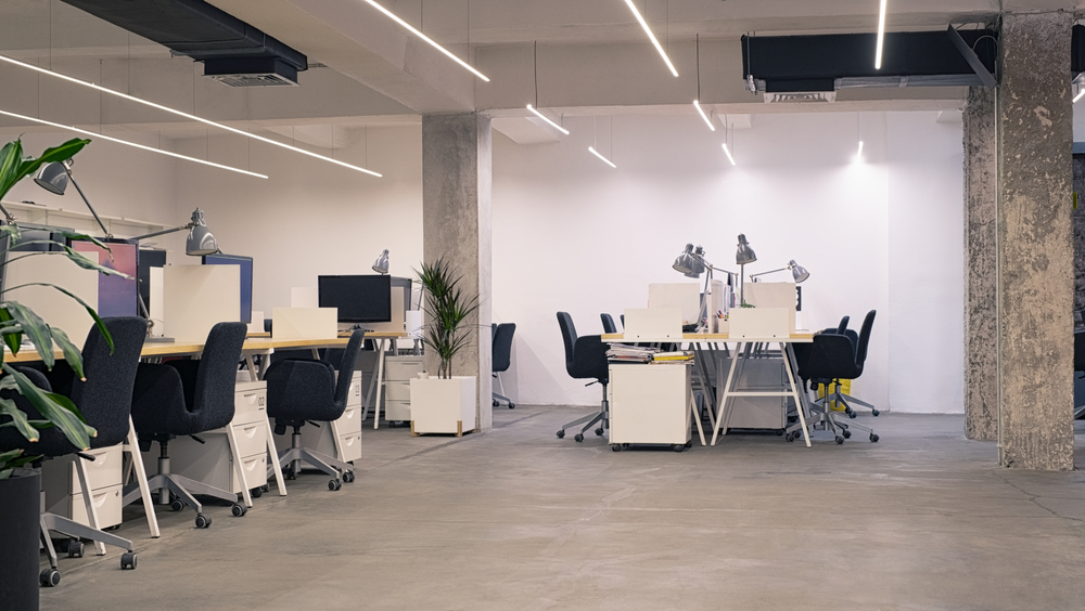 A well organized office is filled with chairs, desks, and plants, but no people.
