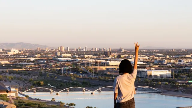 Arizona State University Master of Urban and Environmental Planning primary imager with a somen pointing to the sky and you see the city and river in the distance.
