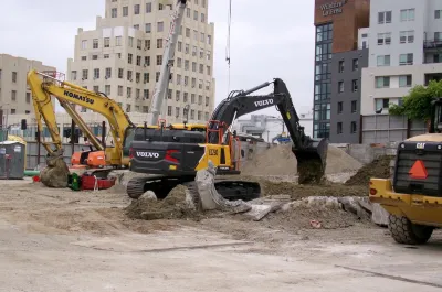 Yellow electric excavator digging at construction site in Los Angeles, California.