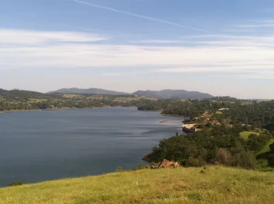 A large reservoir and its dam are shown in golden foothills.