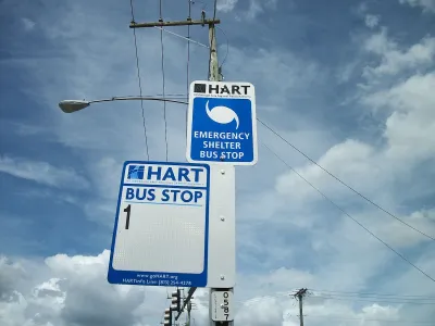 Close-up of HART bus stop sign for Route 1 and hurricane evacuation route sign on street pole in Tampa, Florida.