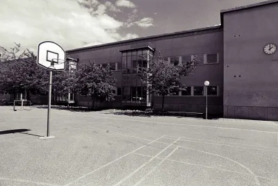Low-saturation image of a concrete schoolyard with basketball hoop