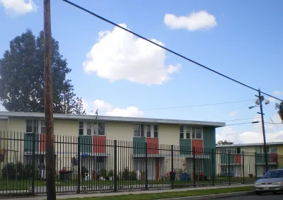 Two-story apartment building behind black iron fence in Pacoima, California
