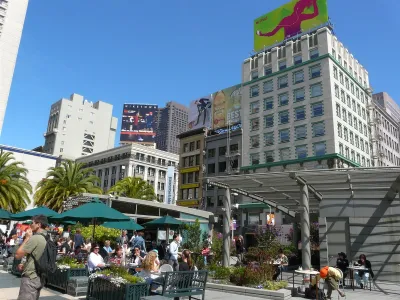 People sitting at outdoor tables with green umbrellas in Union Square, San Francisco.