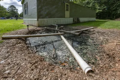 Mobile home with pipe directed into the yard into a pit of standing sewage.