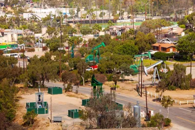 Oil wells scattered across a residential neighborhood in Los Angeles, California on a sunny day.