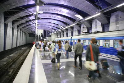 Busy subway station with people walking on platform and train stopped.