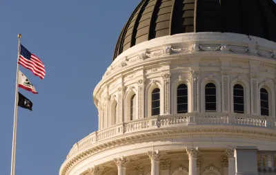 Close-up of Californis state capitol dome with U.S., California, and POW/MIA flags on flagpole.