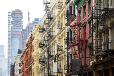 Brick New York City apartment buildings with fire escapes and high-rise under construction in background.