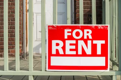 Close-up of red For Rent sign with white text on porck of brick building.