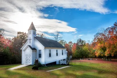 Small white wooden church in rural setting.