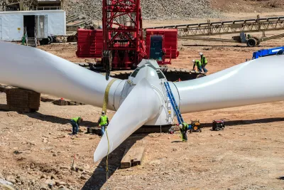 White wind turbine sitting on ground at wind farm construction site.