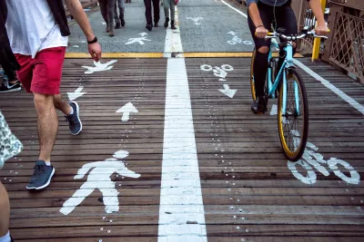 Close-up on wooden section of bike and pedestrian path marked with ped symbols on one side and bike symbols on the other.