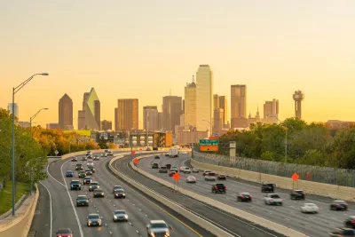 View of Dallas city skyline with moderately busy freeway in foreground at twilight.