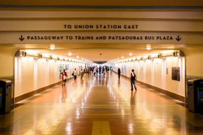 View looking down indoor concourse at Los Angeles Union Station with “To Union Station East” and “Passageway to Trains and Patsaouras Bus Plaza” signs.