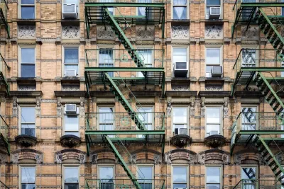 Brick New York City apartment building exterior with fire escape stairs and AC window units.