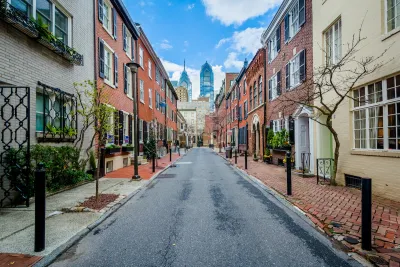 Street with old buildings in Philadelphia, Pennsylvania and modern high-rise buildings in background.