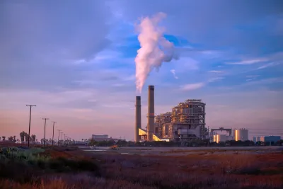 Natural gas power plant with two tall smokestacks against blue and purple sunset sky