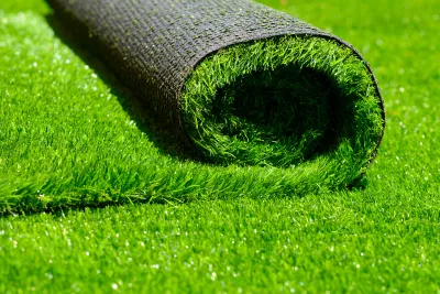 Close-up of roll of green artificial turf laying on more artificial turf.
