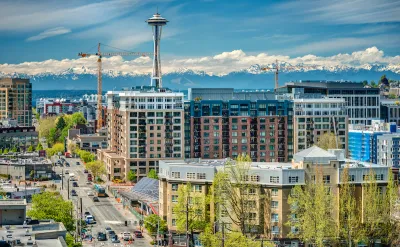View of multistory buildings under construction in downtown Seattle, Washington with Space Needle and Mount Rainier in background.