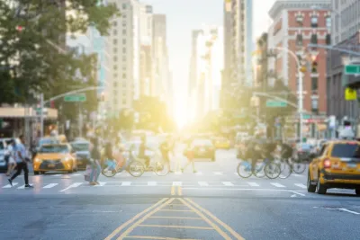 Busy crosswalk with people and bikes in New York City on a bright afternoon.