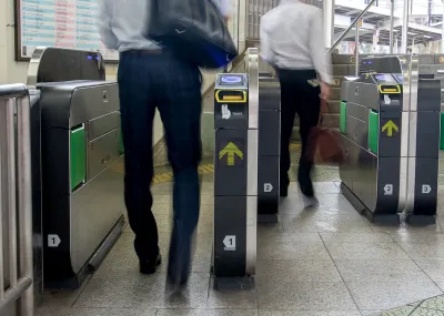 People entering modern fare gates in subway station.