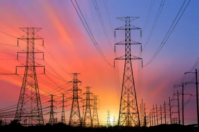 High voltage power line towers sillhouetted against colorful sunset sky.