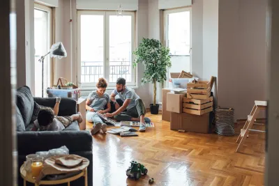 Man, woman, and child in apartment with moving boxes and crates.