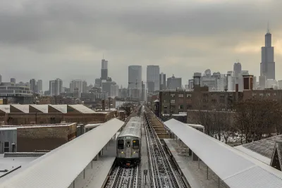 Train on elevated track on snowy city landscape with Chicago skyline in background.
