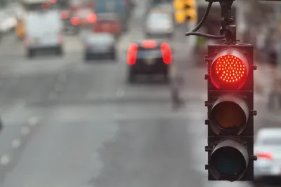 Close-up on red traffic light with blurred street in background.
