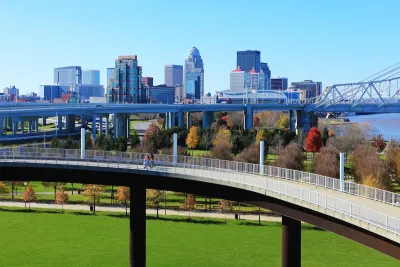 Skyline of Louisville, Kentucky with pedestrian walkway in foreground and vehicle bridge.