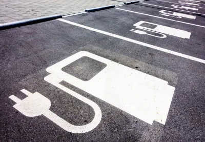 Close-up of white electric car charging symbol on black pavement in parking spaces.