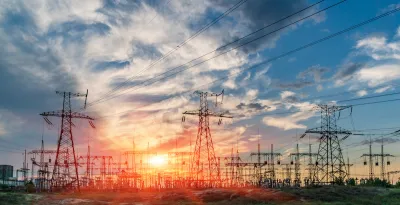 View of power towers at electric distribution substation against colorful sunset sky.