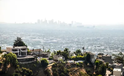 View of large mansions in Hollywood hills with downtown Los Angeles skyline in background.