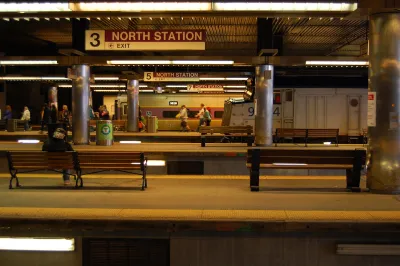 Few passengers waiting in subway station with multiple platforms and "North Station" signs in Boston, Massachusetts
