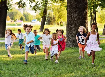 Group of children running toward the camera on a green lawn