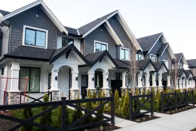 ROwn of grey and white townhomes with gabled roofs and front porches.