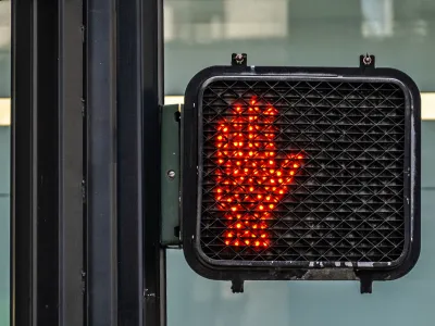 Red hand lit up as "don't walk" pedestrian signal.