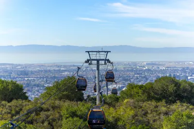 View of aerial tram cars at Oakland Zoo with Oakland, California neighborhoods in background.
