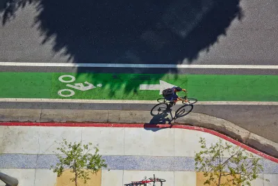 Bird's eye view of green painted bike lane with one cyclist.