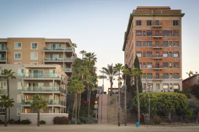 Vintage multi-story brick apartment building and modern concrete and glass apartment building separated by a steep public stairway in Los Angeles, California.