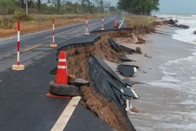 Asphalt road on coast with collapsed segments from erosion.