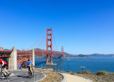 Two cyclists on a paved bike path overlooking the Golden Gate Bridge, San Francisco, California.