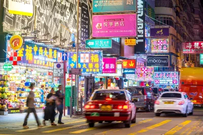 Cars and pedestrians on Hong Kong street at night.