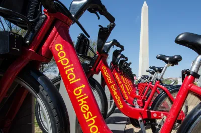 Close-up of red Capital Bikeshare bikes with Washington Monument in background.