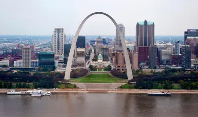 View of the Gateway Arch with Mississippi River in foreground and St. Louis skyline in background.