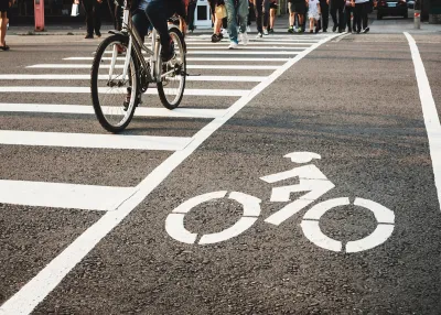Low angle of pedestrians and a bicycle crossing the street at an urban crosswalk.