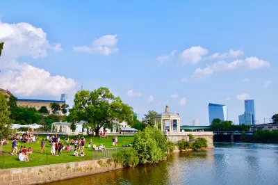 Riverfront park in Philadelphia with white gazebo and skyscrapers in background.