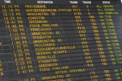 Close-up of old-fashioned trains departure board with yellow text on black background in Boston, Massachusetts train station.
